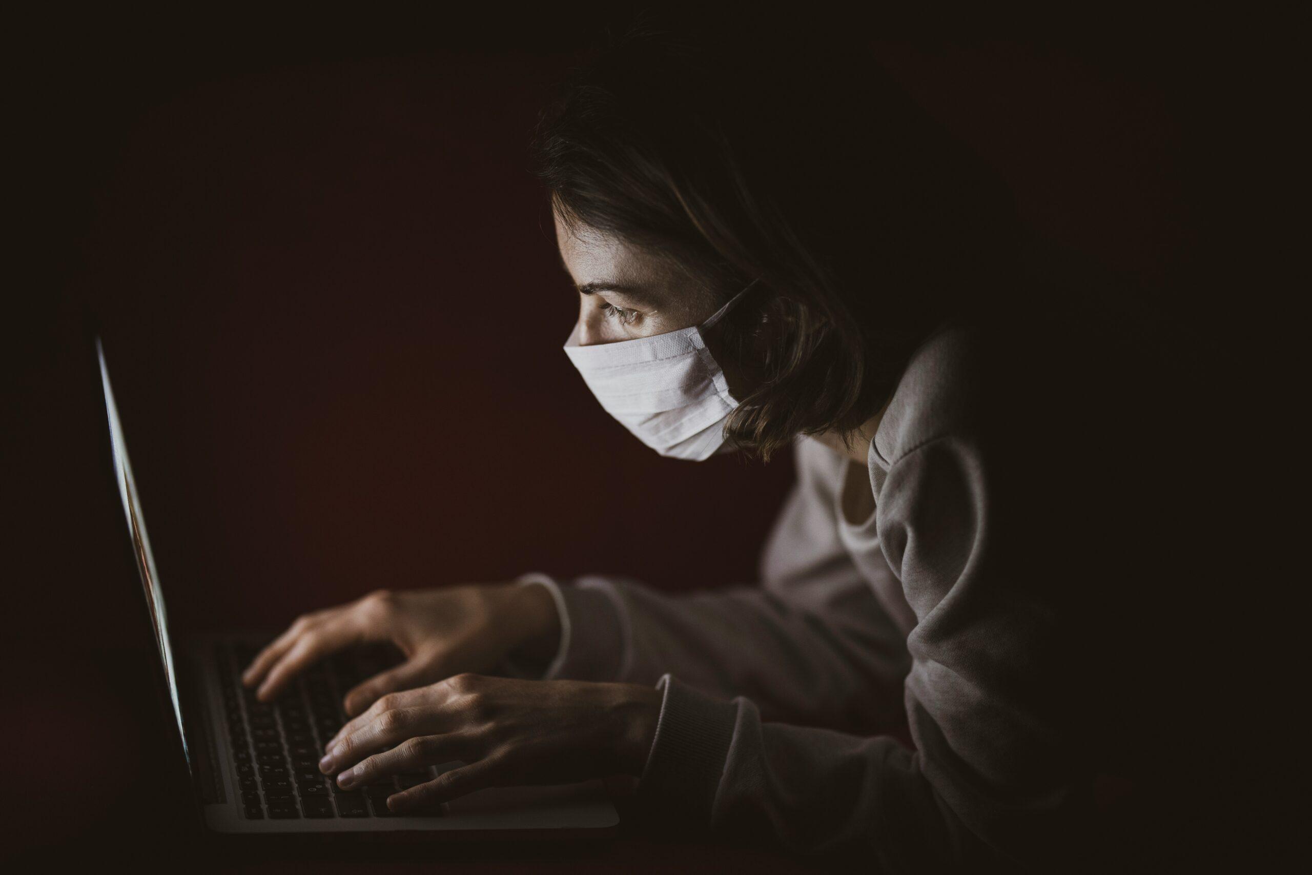 woman wearing mask on laptop
